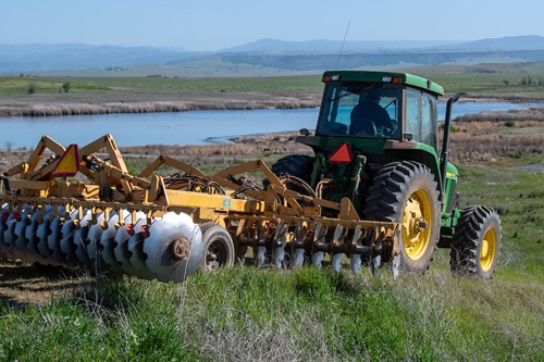 A tractor discs land near a wildlife area. SOURCE: Department of Water Resources